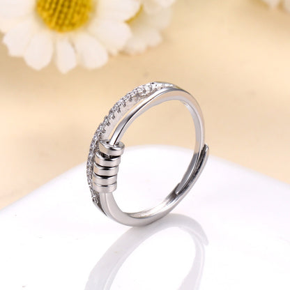 Anillo Axia: Anillo moderno con patillas paralelas y detalles cilíndricos de metal pulido.