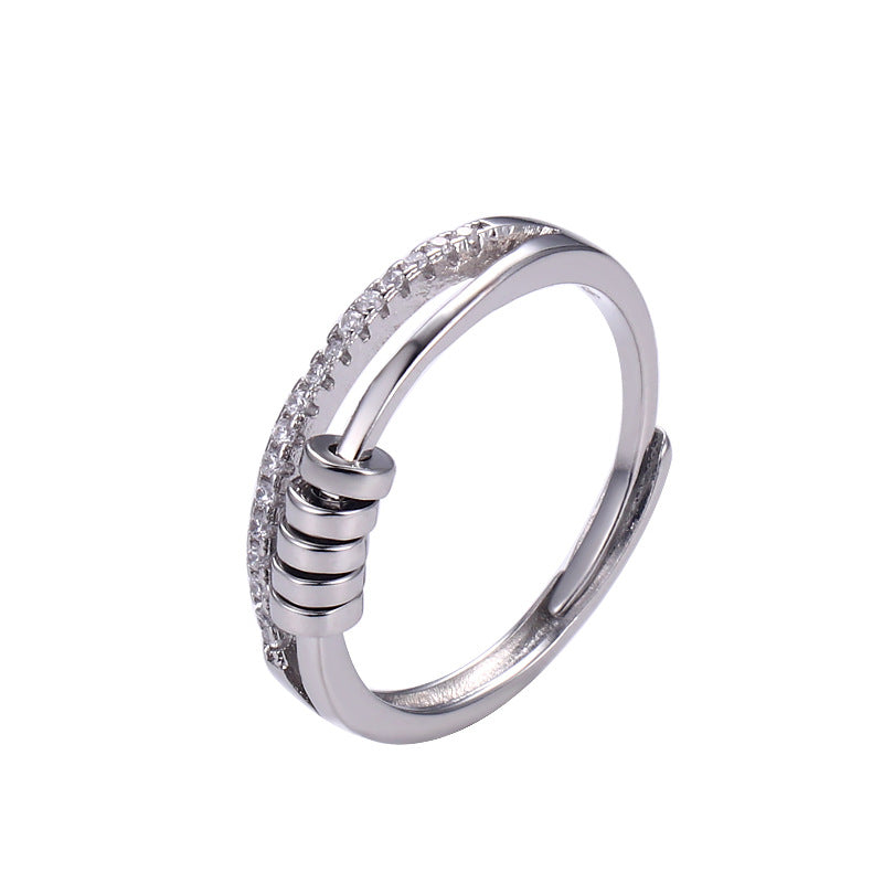 Anillo Axia: Anillo moderno con patillas paralelas y detalles cilíndricos de metal pulido.