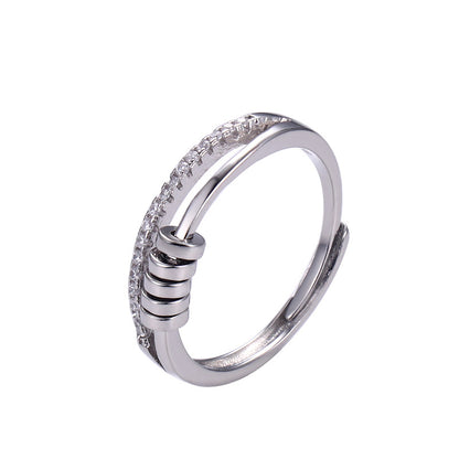Anillo Axia: Anillo moderno con patillas paralelas y detalles cilíndricos de metal pulido.