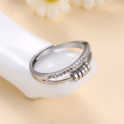Anillo Axia: Anillo moderno con patillas paralelas y detalles cilíndricos de metal pulido.